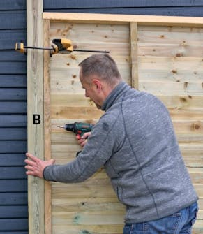 Nurkkatolppien kiinnittäminen pihavaraston takaseinään Nurkkatolppien kiinnittäminen pihavaraston takaseinään